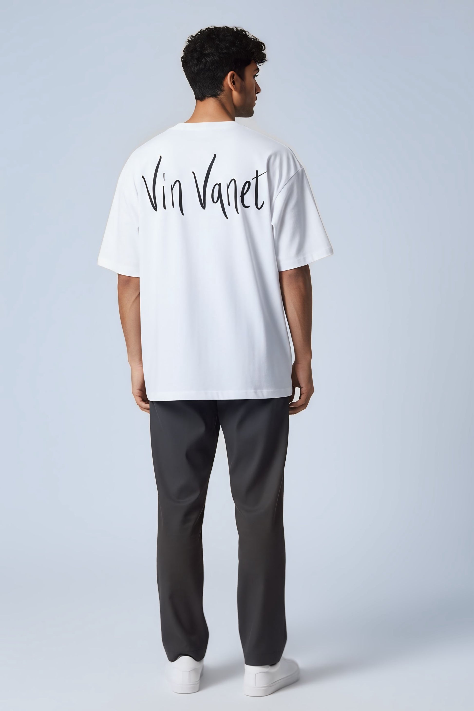 Person wearing a white t-shirt with 'Vin Vanet' text on the back against a light gray background