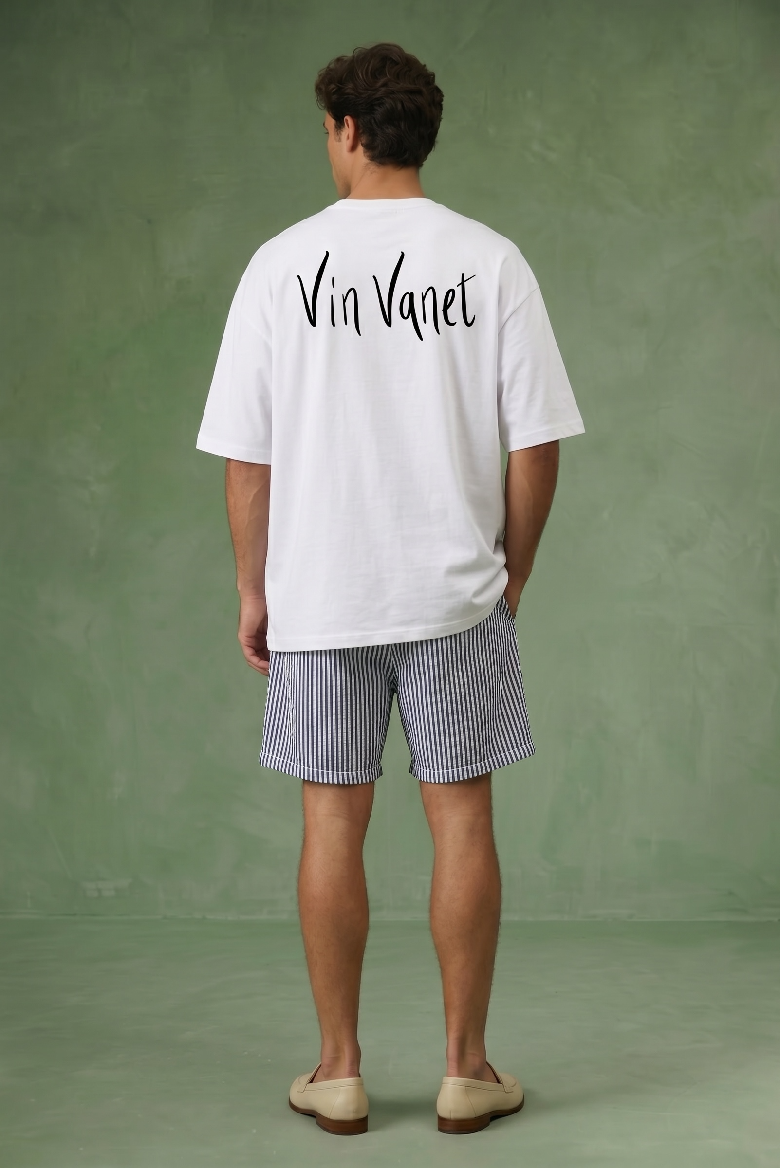 Man wearing a white t-shirt with 'Vin Vanet' text on the back against a green background