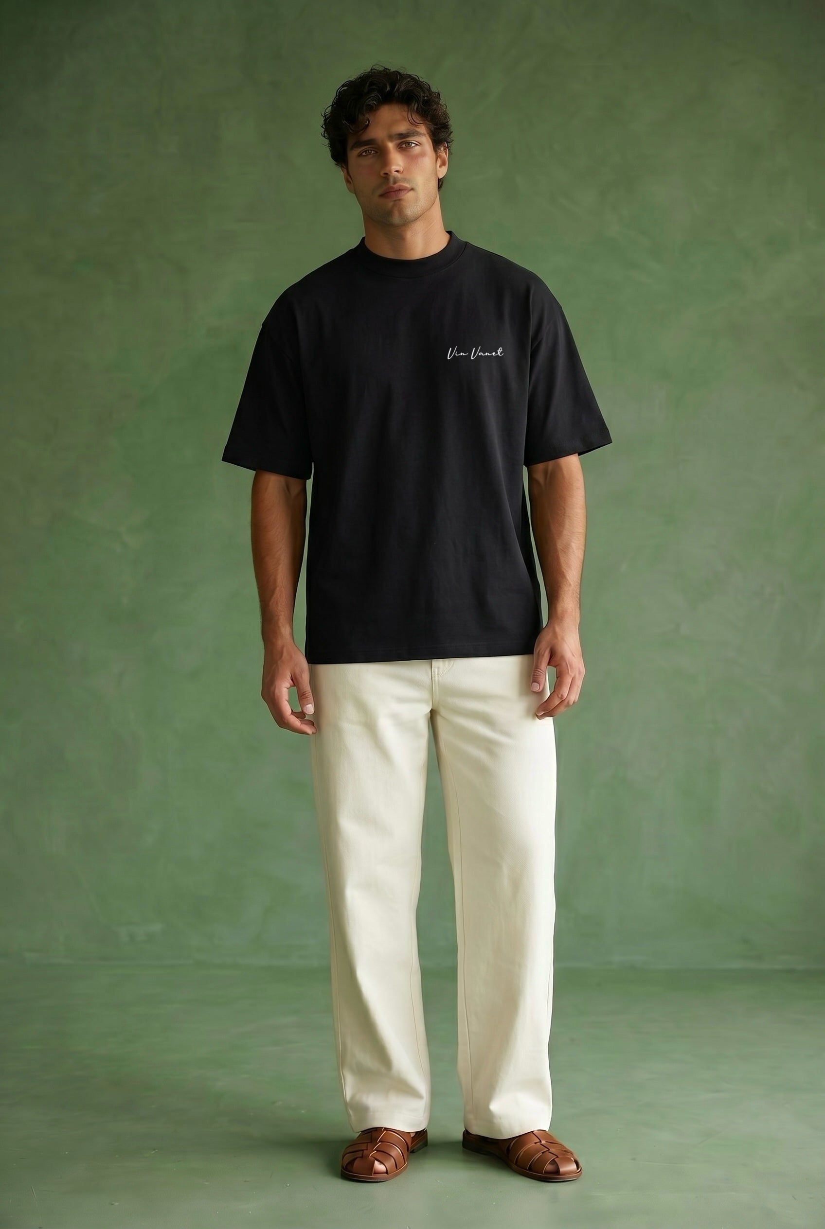Man wearing a black t-shirt and white pants against a green background